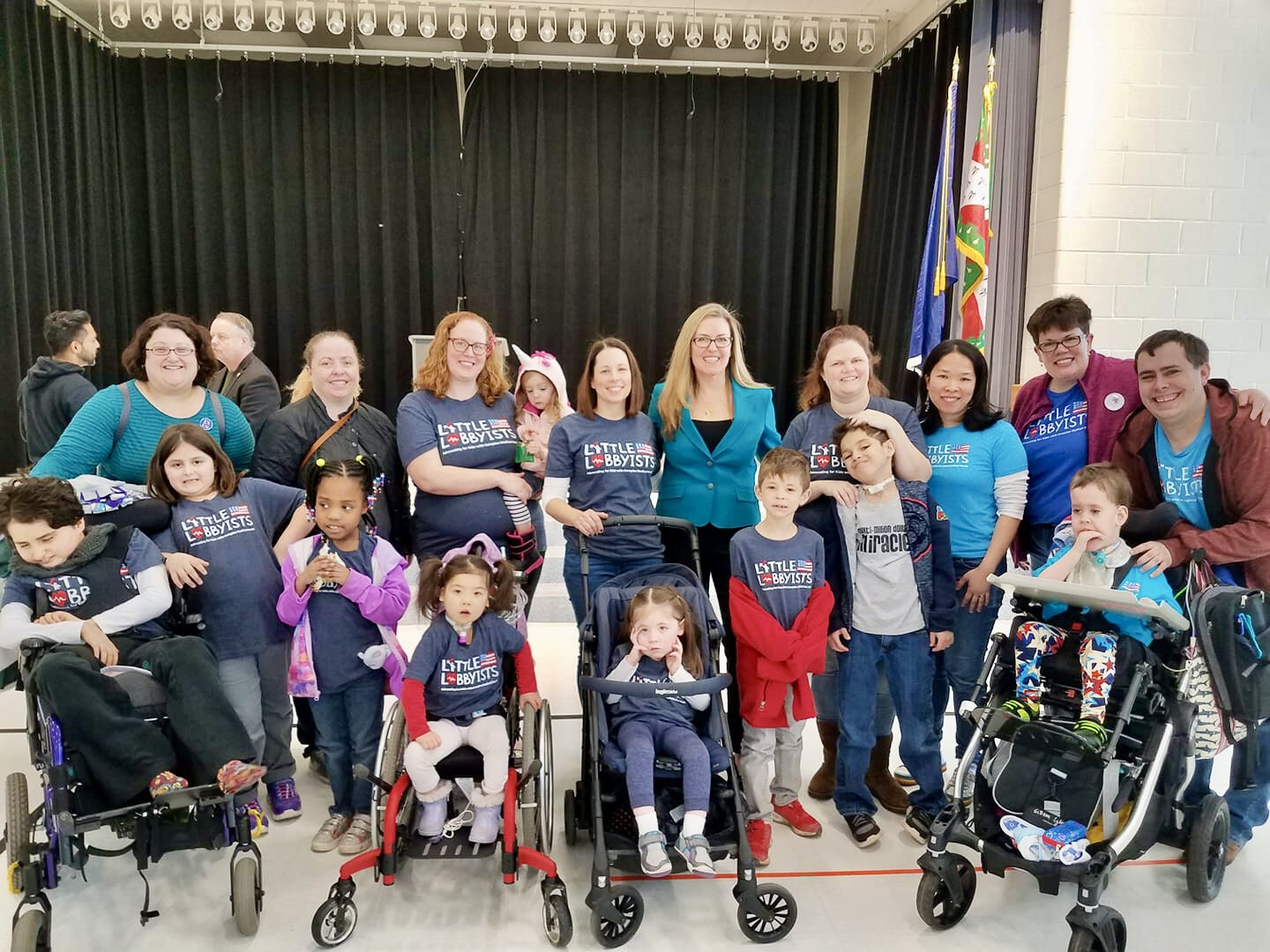  A large group of Little Lobbyists poses with a member of. Congress in front of curtains. 