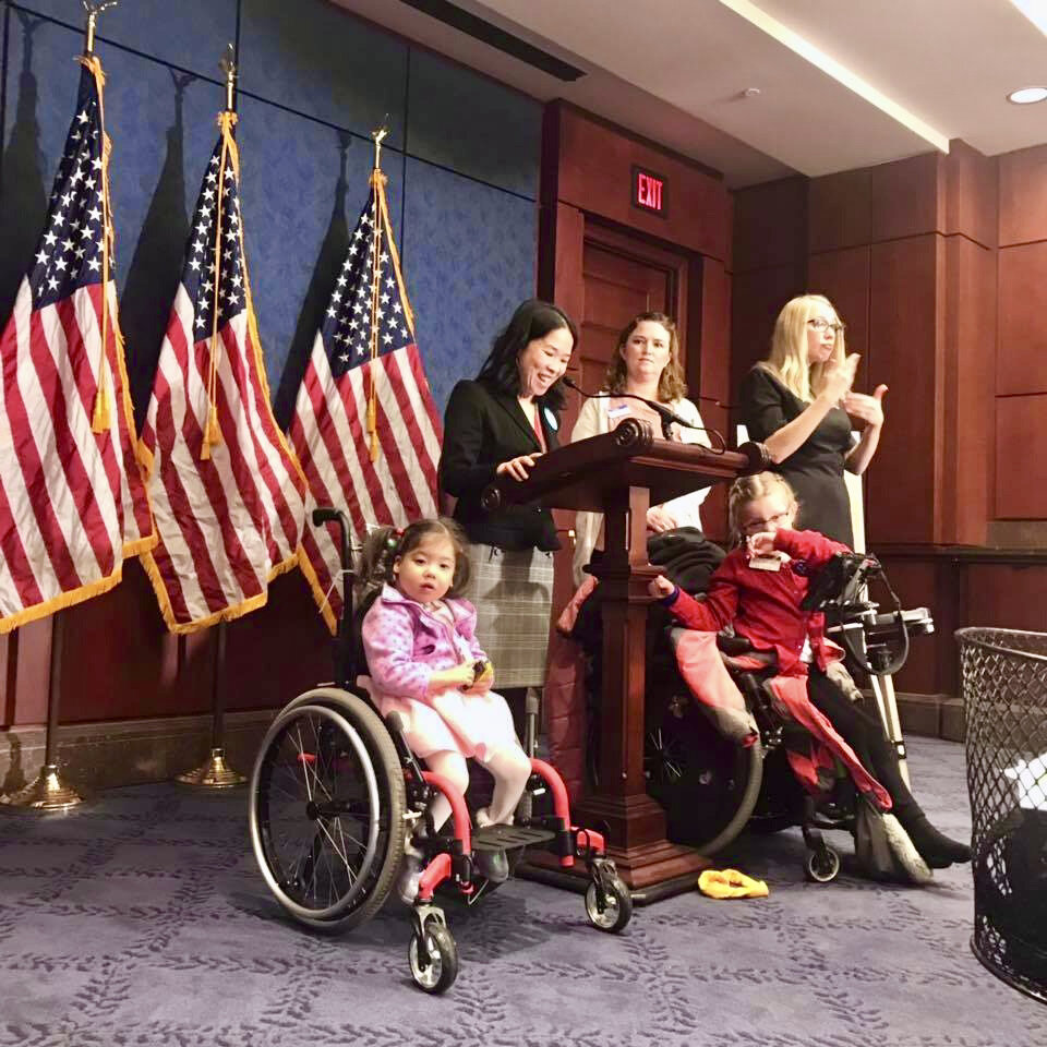  Two members of Little Lobbyists speak at a podium in the U.S. Capitol at the launch of a disability rights bill. 