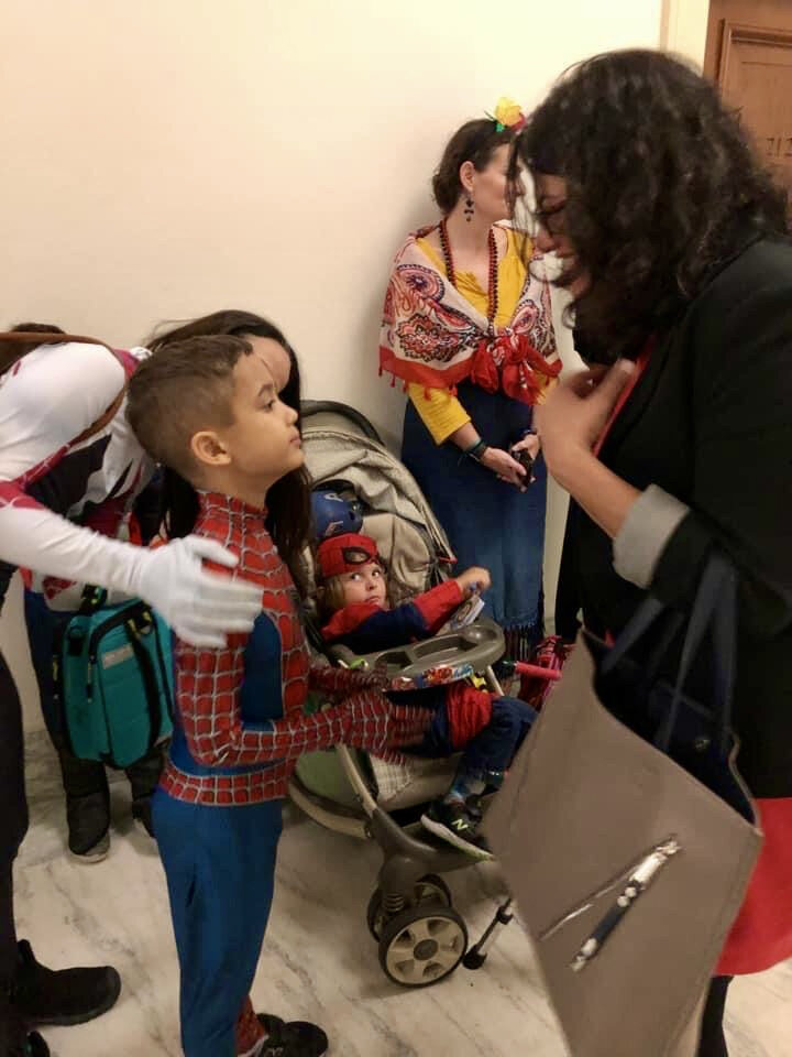  A young boy wearing a superhero costume speaks with a member of Congress in a hallway in one of the congressional office buildings.  