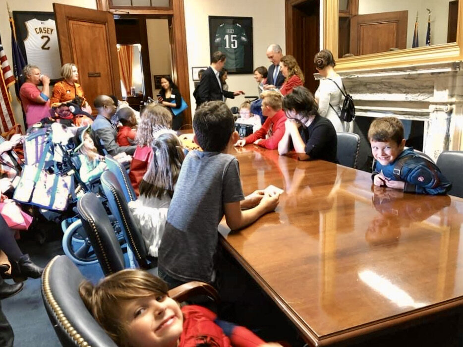  Little Lobbyists kids pile around a large conference table during a Halloween on the Hill day. 