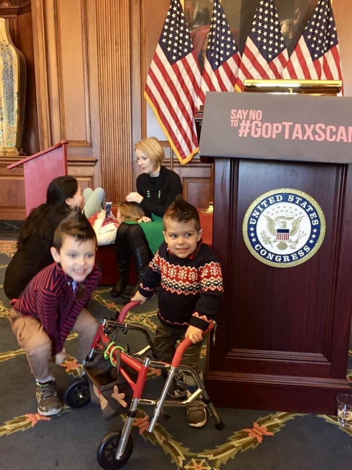  Two young boys play near a podium with a legislative seal. American flags are in the background. 