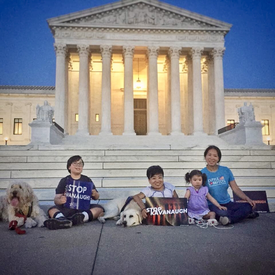  Several members of Little Lobbyists, wearing colorful LL t-shirts, pose in front of the U.S. Supreme Court, lit from within in the early evening. 