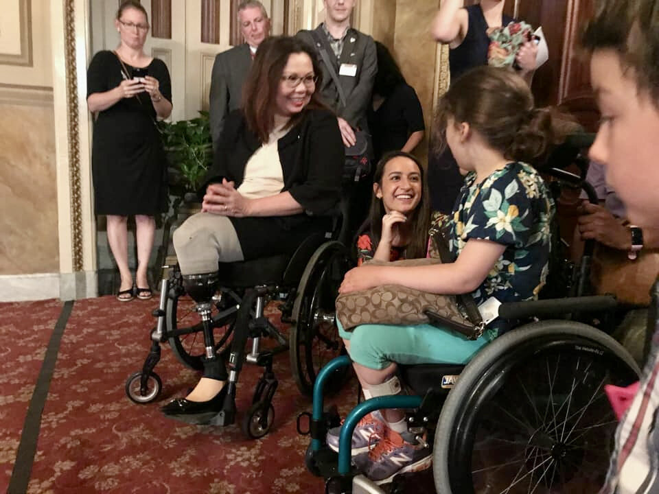 A young girl who is a wheelchair user poses with a U.S. Senator who is also a wheelchair user. 