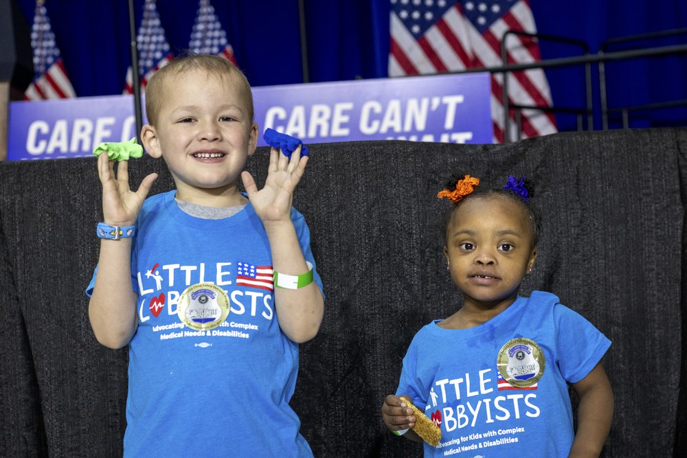  Gabe and Destiny pose in front of the stage, which is all in blue and white with American flags. 