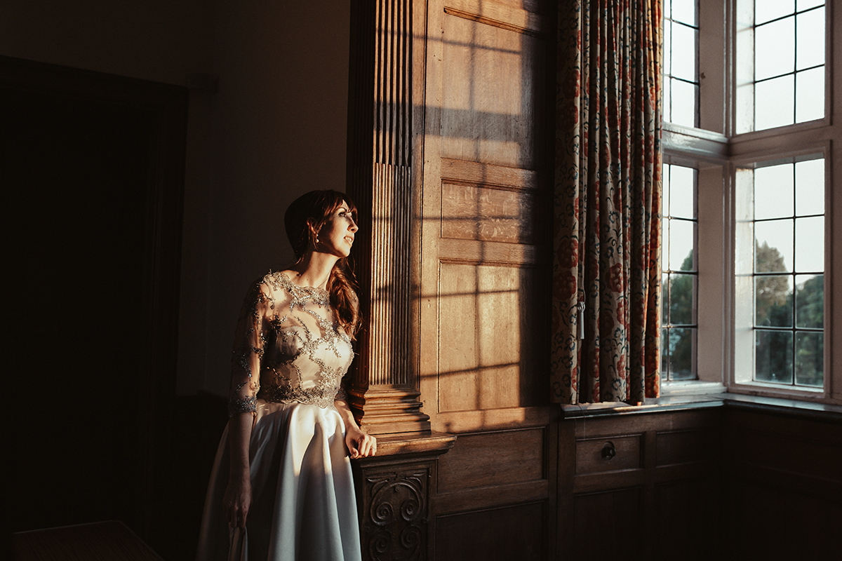 Bride standing in window light Sophie Lake Photography