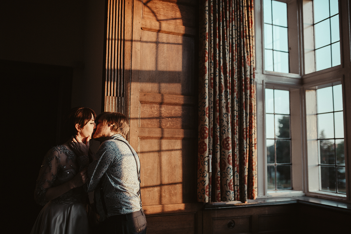 Bride and Groom kissing near window Sophie Lake Photography