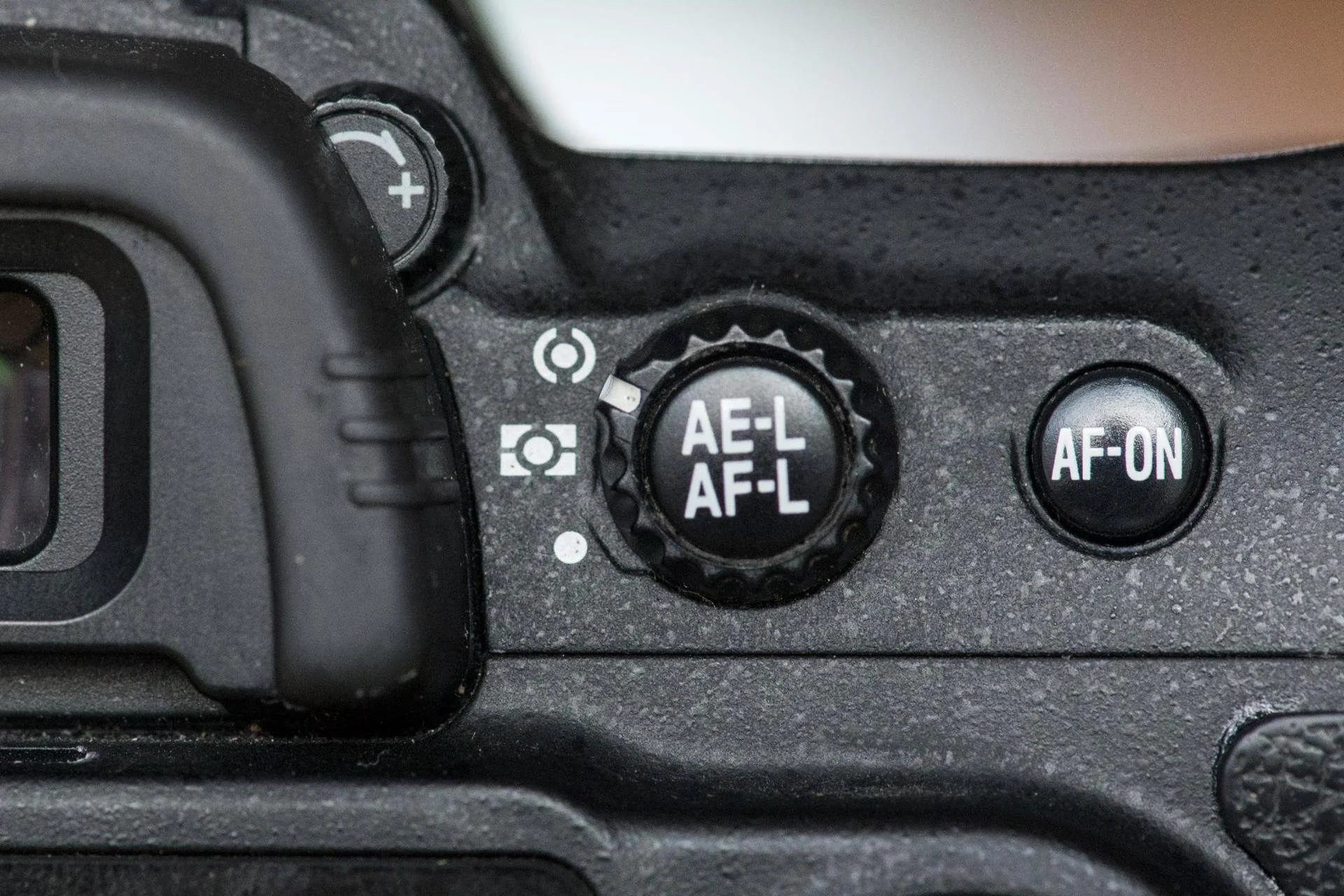 Close-up of a camera's mode dial showing settings for aperture, shutter, and autofocus, with a button labeled 'AF-ON' nearby.