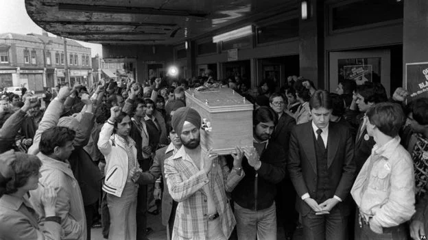 April 1979: People raise their fists as they see Blair Peach’s coffin carried at his funeral. Image: BBC