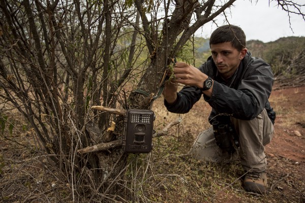 Chris Jordan sets a camera trap by the side of a trail