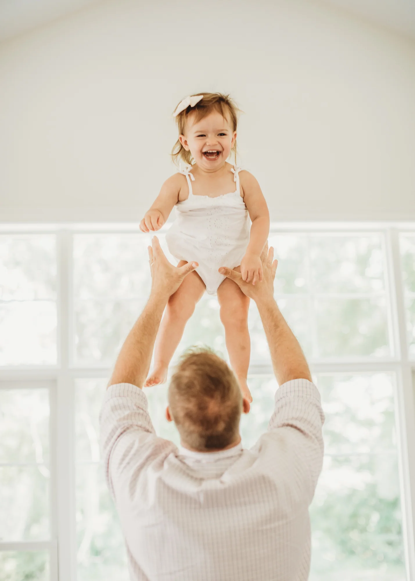 Dad tossing big sister in the air during Wayland, MA in-home newborn session. Greater Boston family photographer. Lifestyle photography.