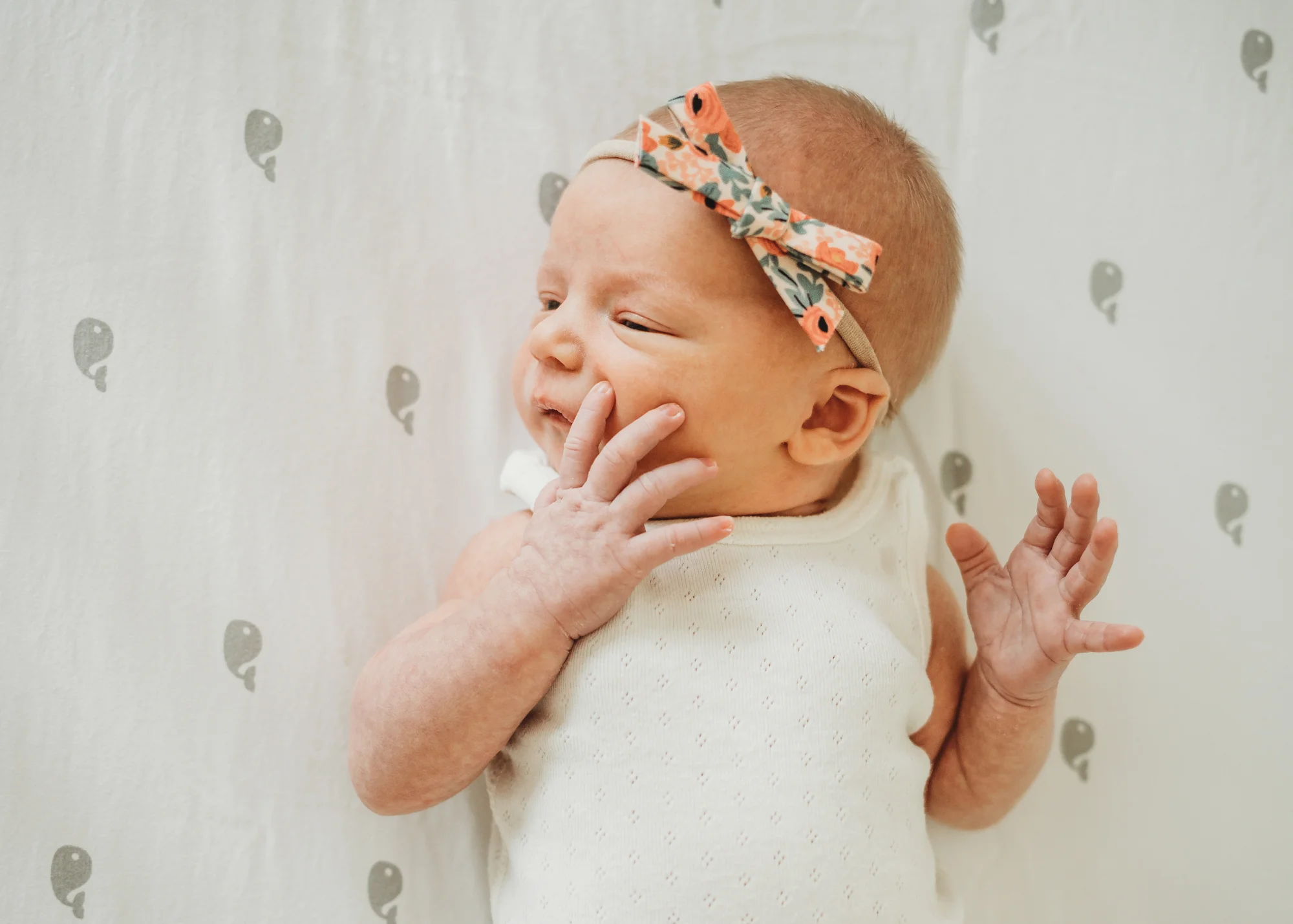 Newborn baby girl in her crib in Wayland, Massachusetts. How to choose outfits for your in-home newborn photographer session.