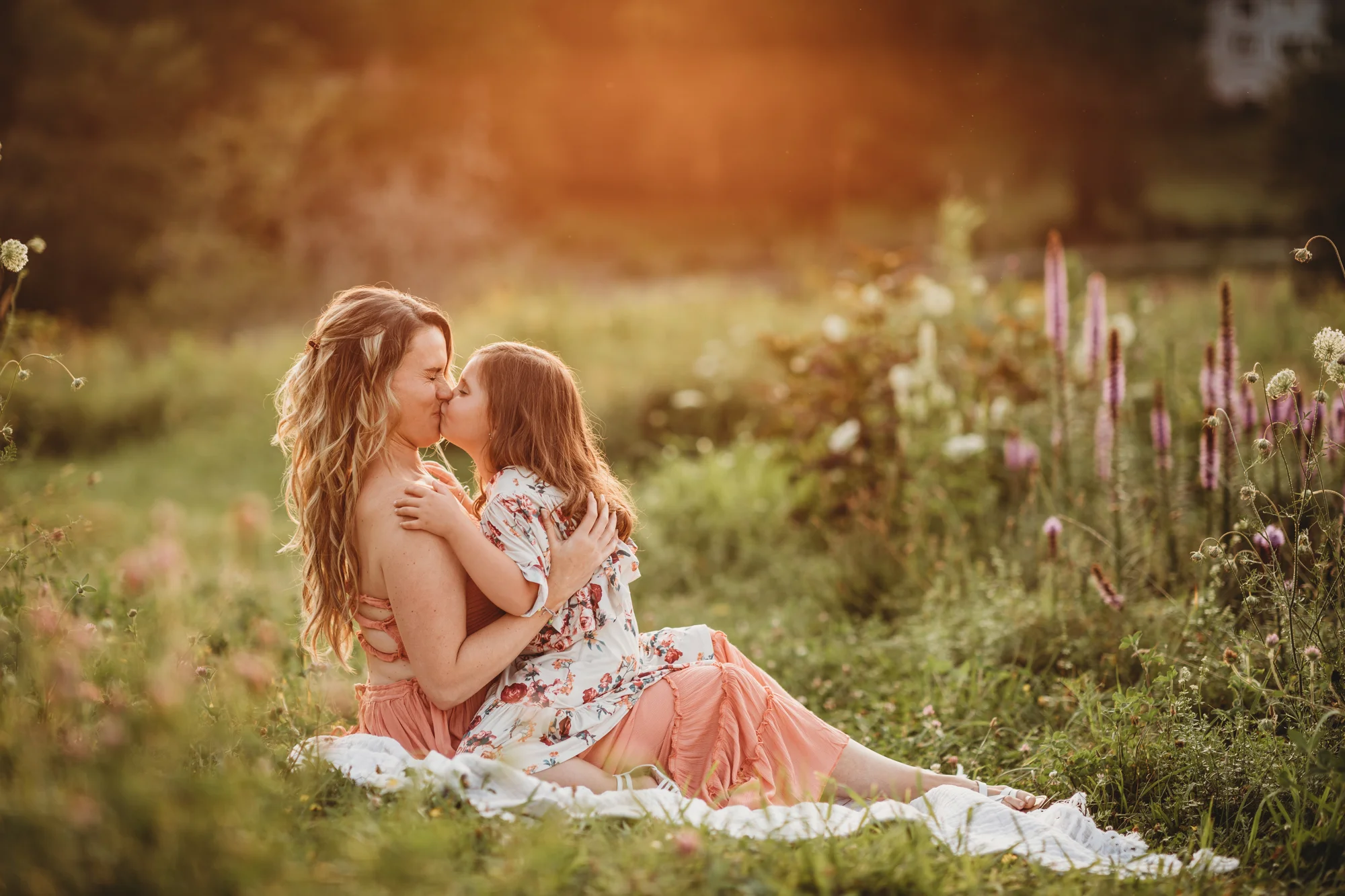 Mom laughing as daughter gives her a big kiss during their Framingham, Massachusetts family photography session. Golden hour in Greater Boston. Natural light lifestyle photography.
