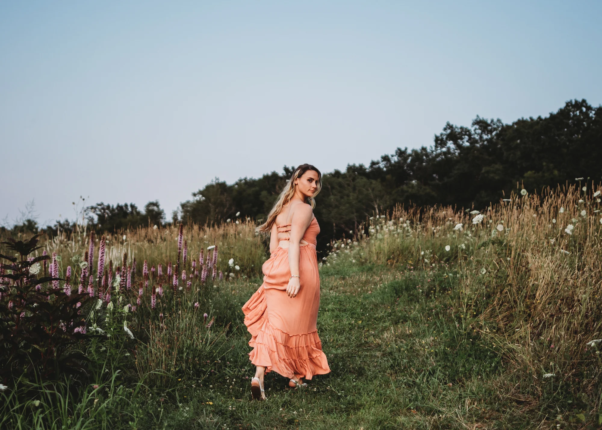 Beautiful mom walking uphill among the wildflowers in Framingham, Massachusetts during her Greater Boston family photography session.