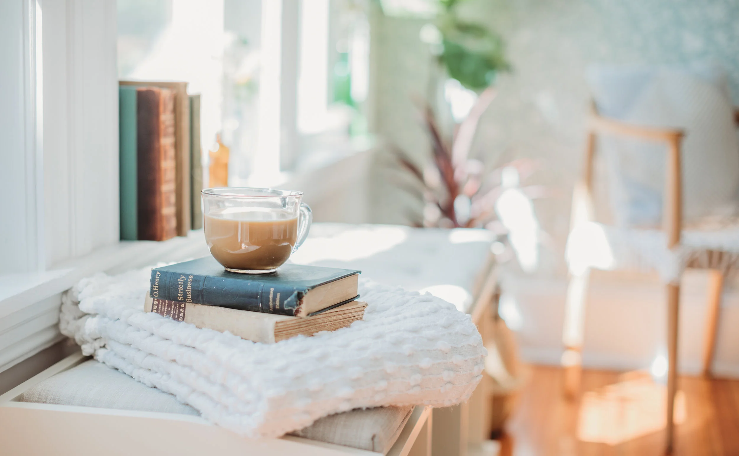 Coffee cup on a stack of books in a bright and sunny office. Boston branding photographer Joy LeDuc shares ideas on props to include in your personal branding photo session.