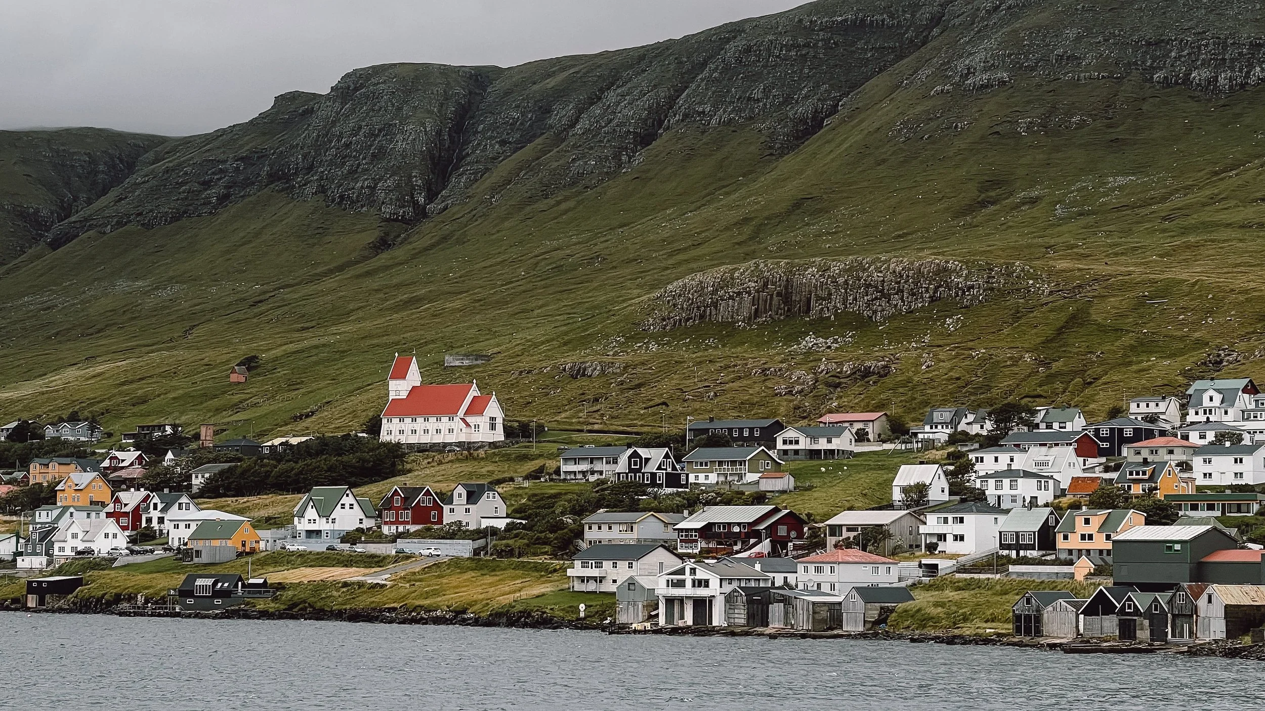 View of Tvoroyri from ferry with large red and white church set against mountains