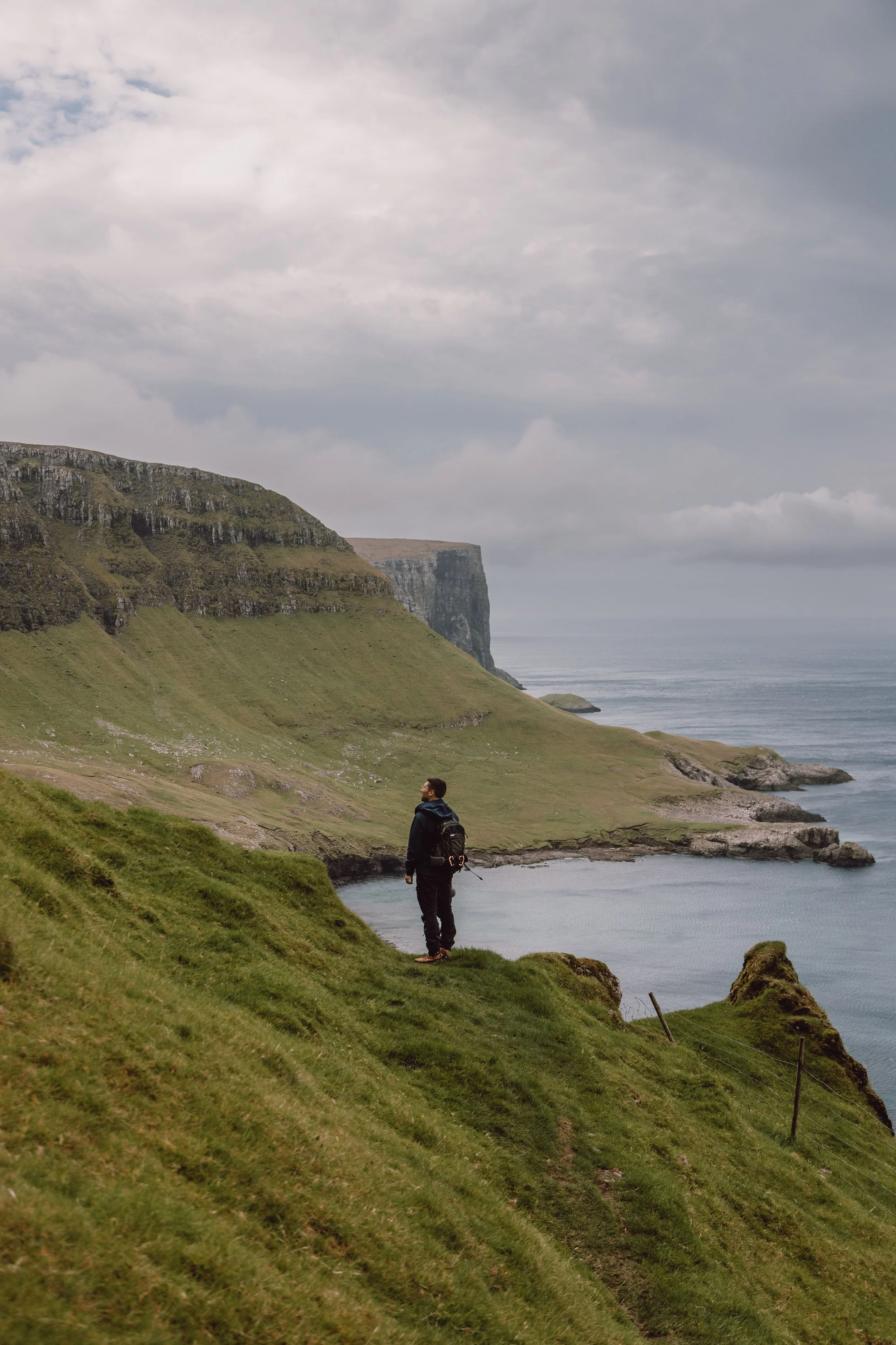 man standing looking at coastal views on Hvannhagi hike in Suduroy