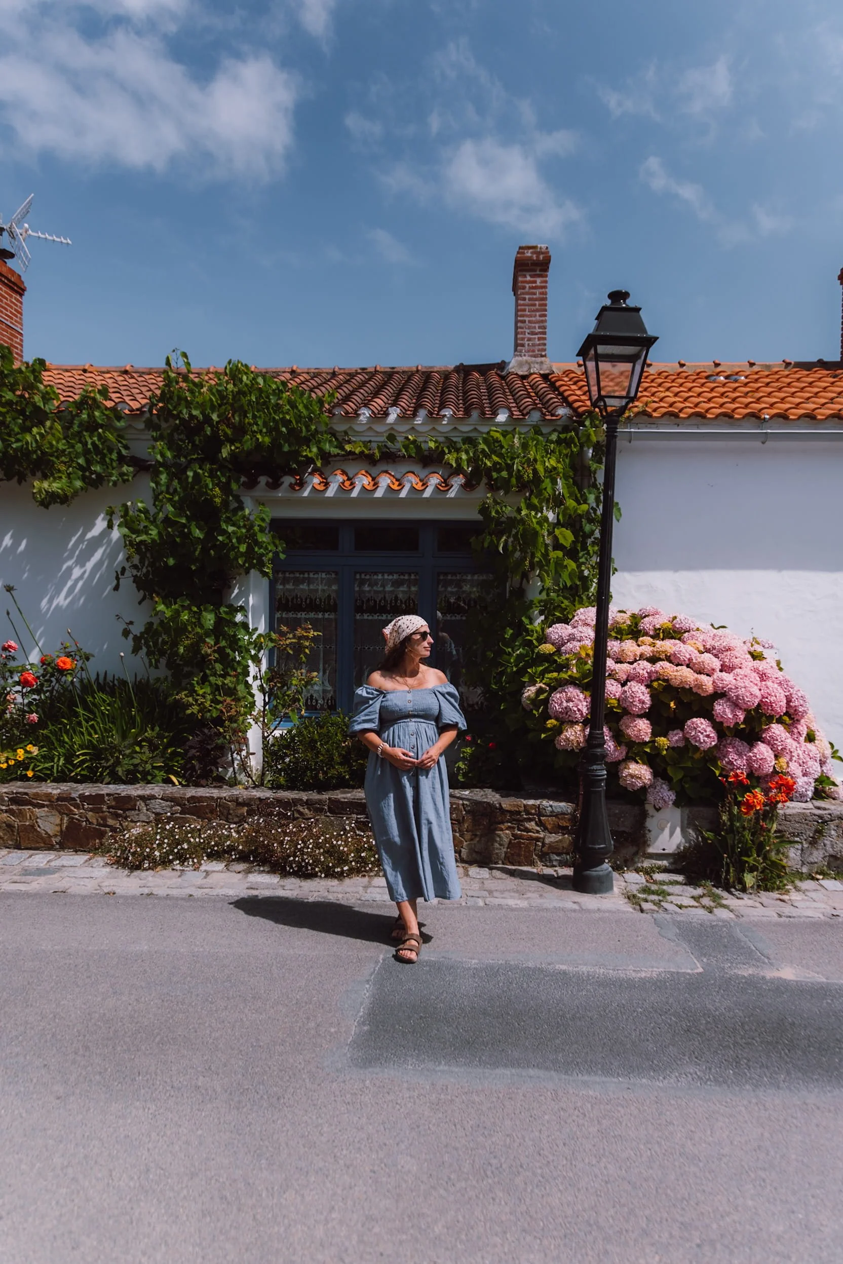 woman standing infront of white house with flowers and vines