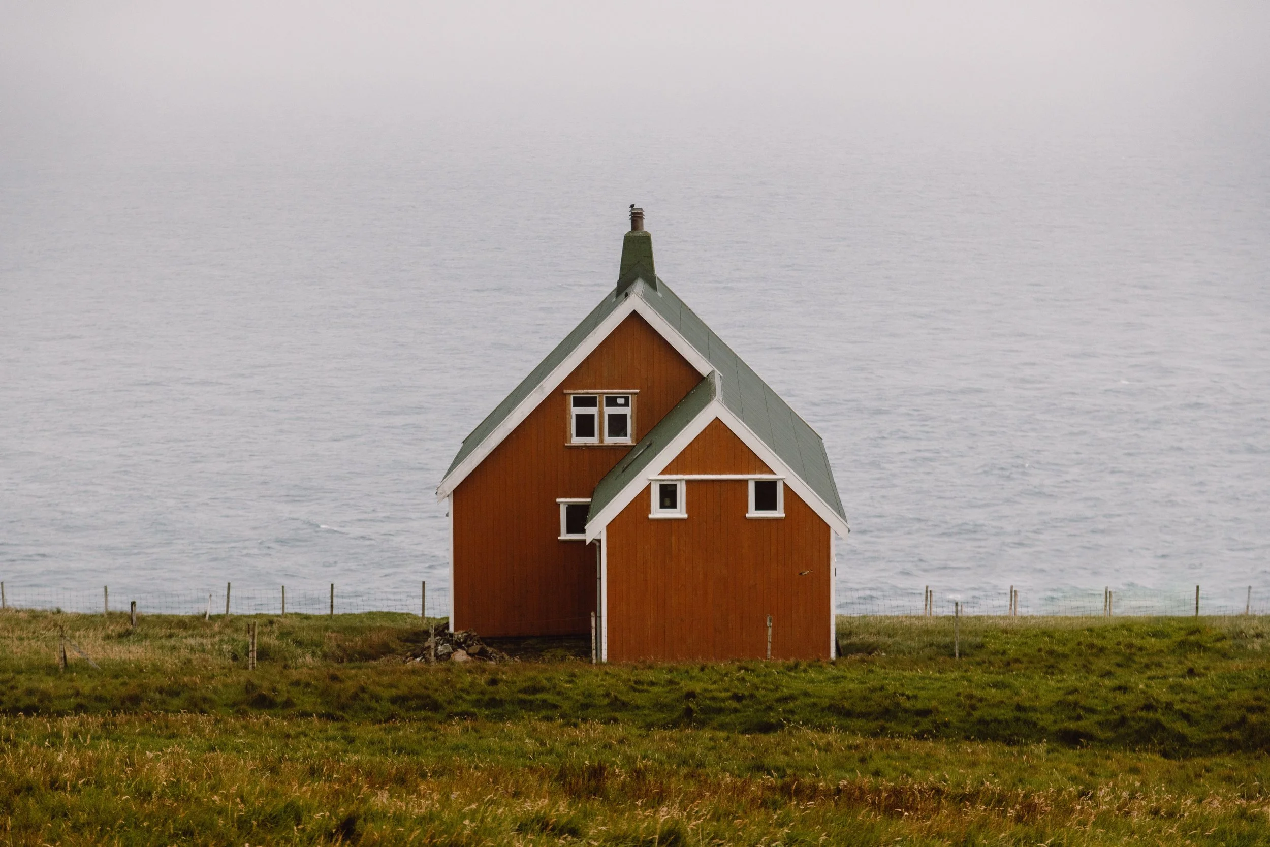 Famous yellow house on Suduroy with green roof and ocean in background