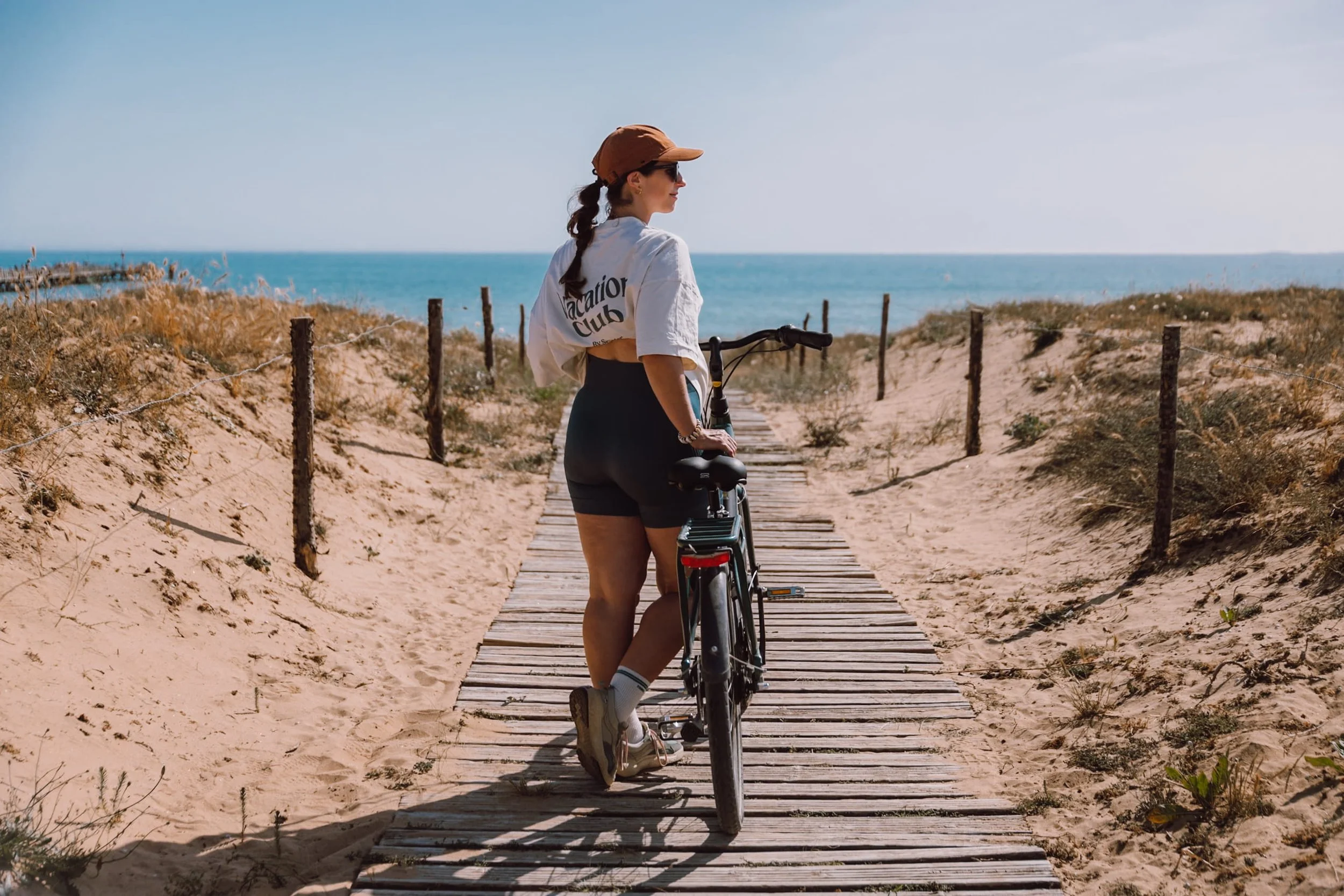 woman with bike on wooden boardwalk with sea view in Saint Jean de Monts