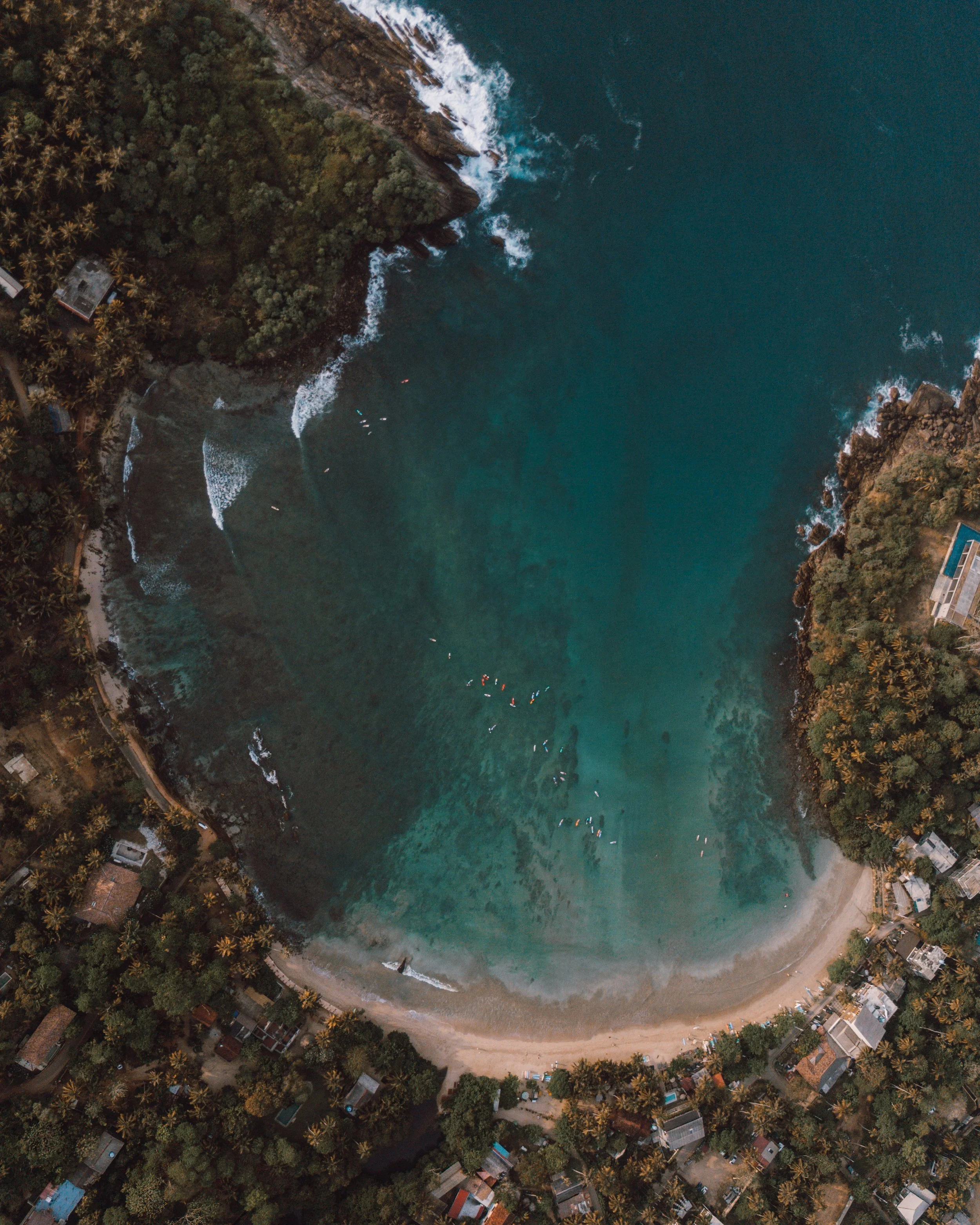 aerial photo of Hiriketiya bay with surfers in the water