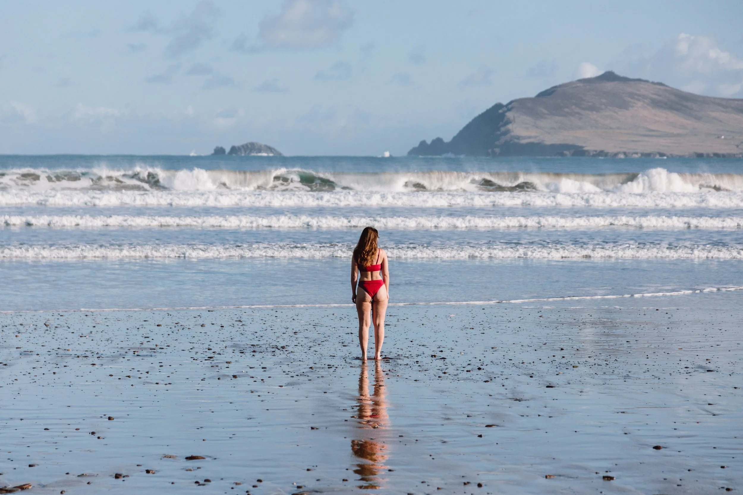 Dingle peninsula woman standing on smerwick harbour beach with mountains in background
