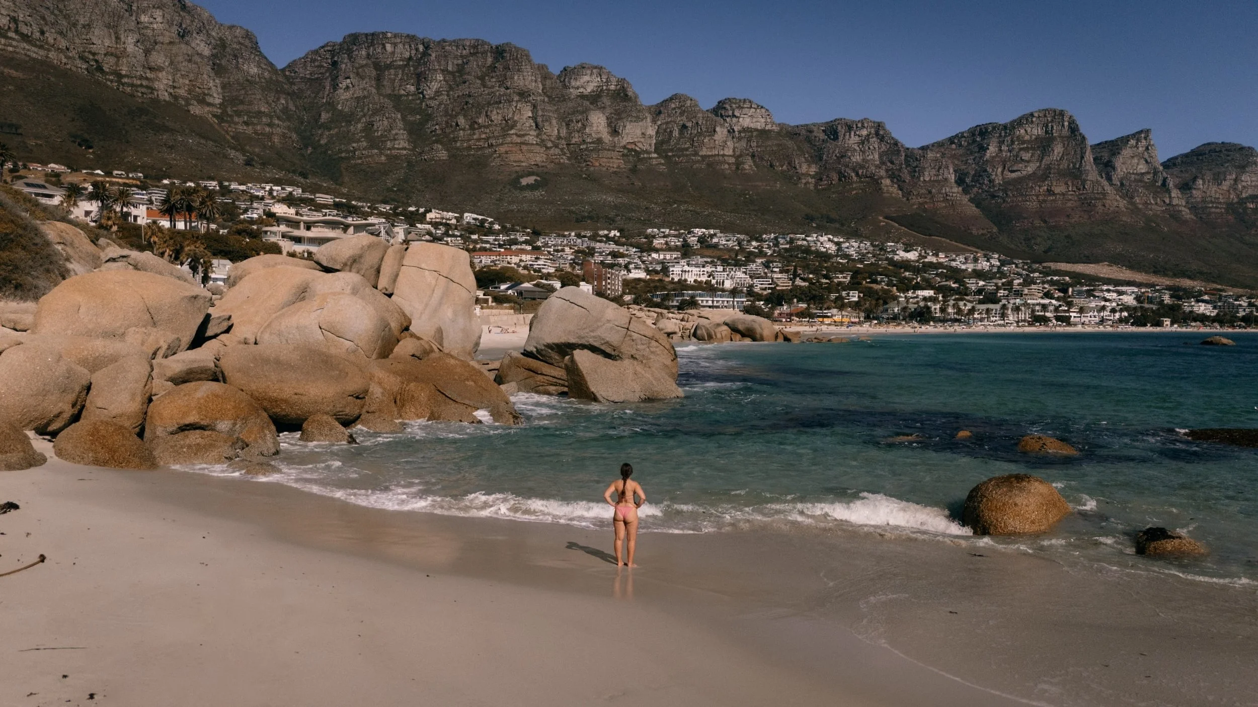 woman on beach near camps bay with twelve apostles in background