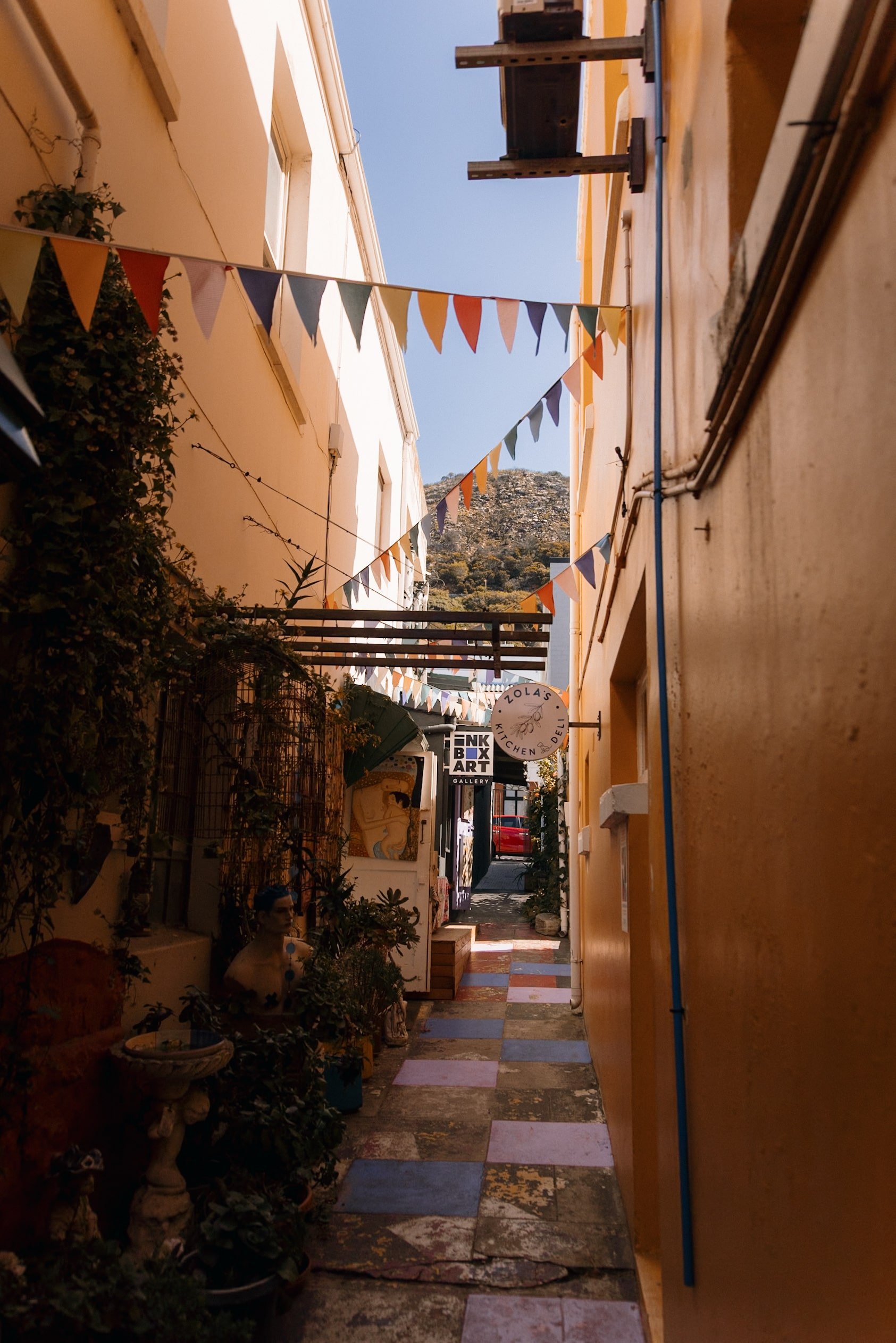 colourful narrow street in Kalk Bay with rainbow flags and art on walls