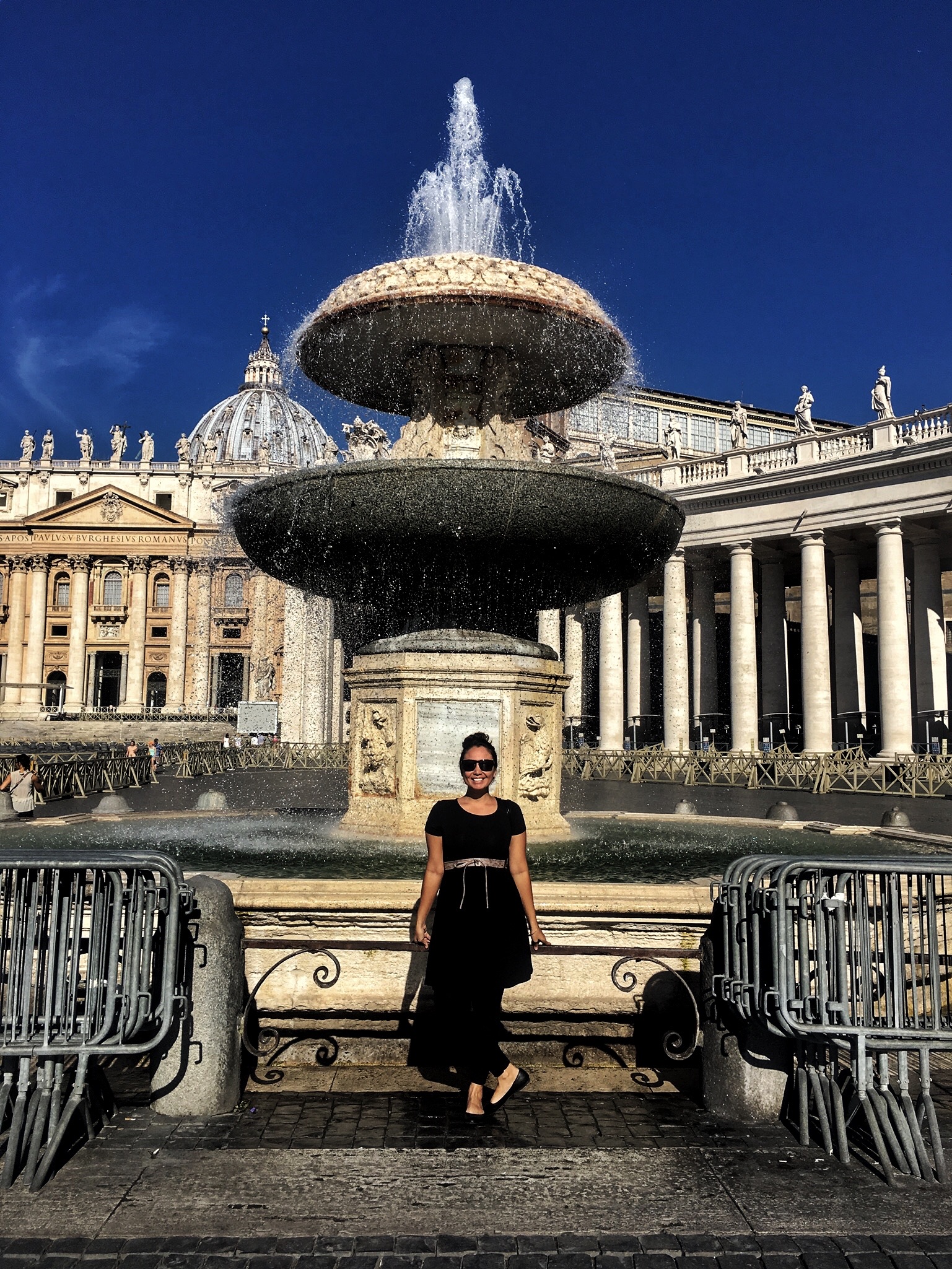 Naomi posing by a fountain in the square outside the basilica.