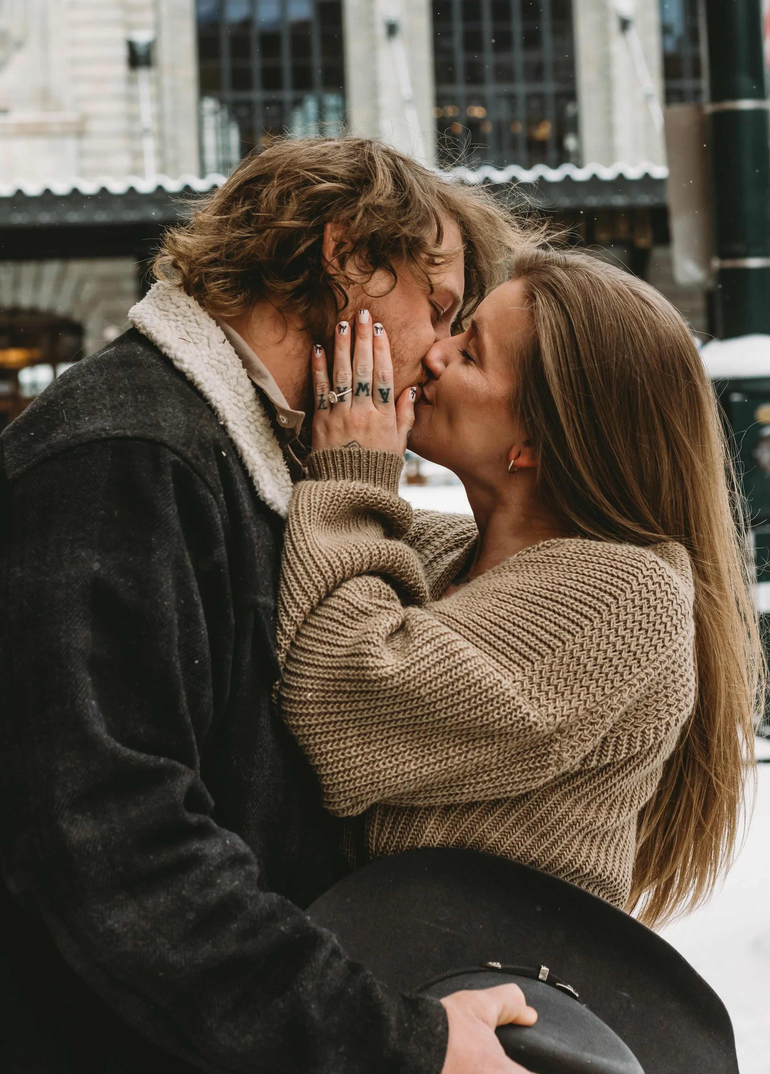 A couple kissing outdoors, with the woman touching the man's face.