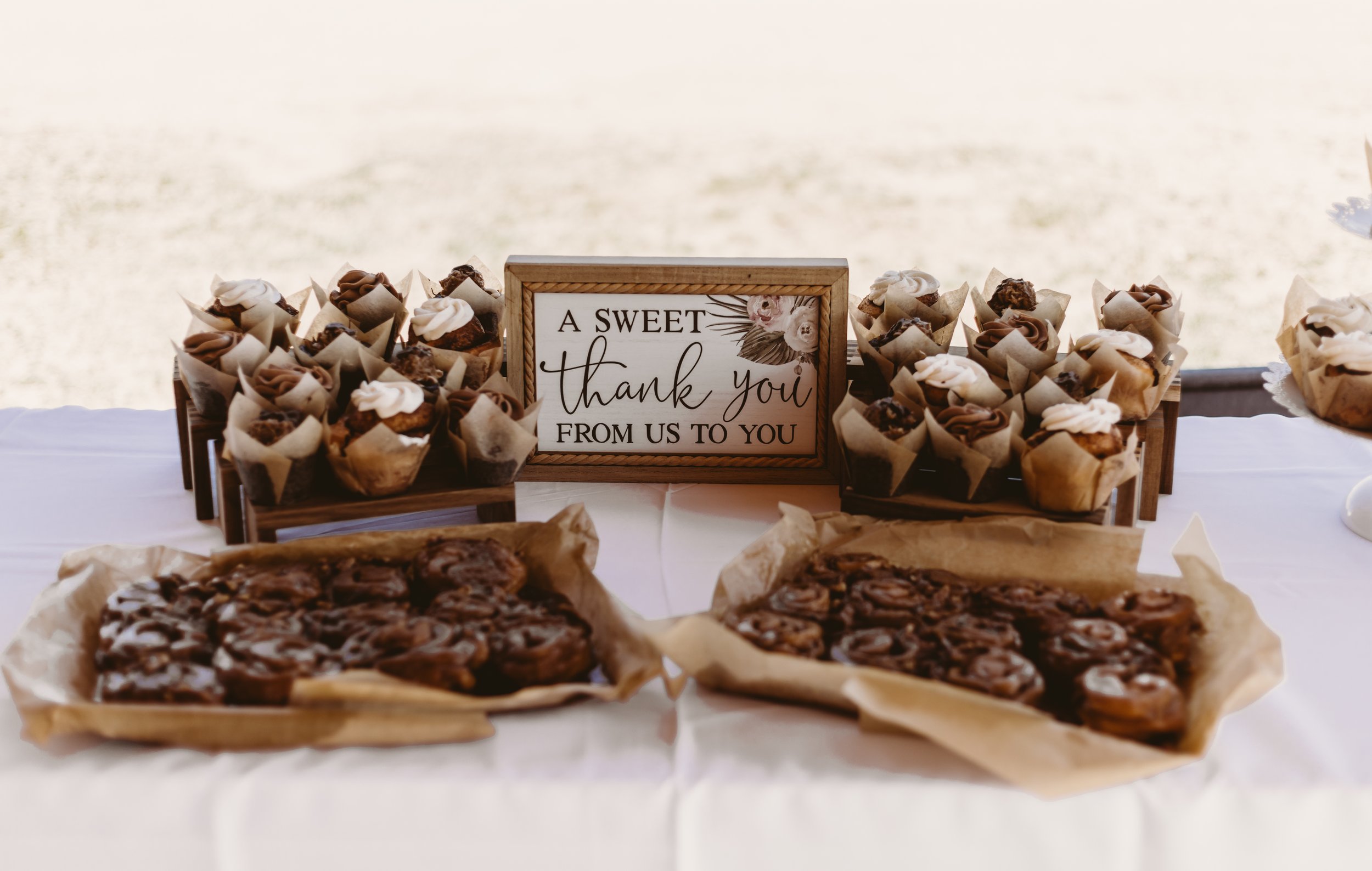 Tray of assorted brownies and baked goods with a decorative sign saying "A sweet thank you from us to you" in the center.