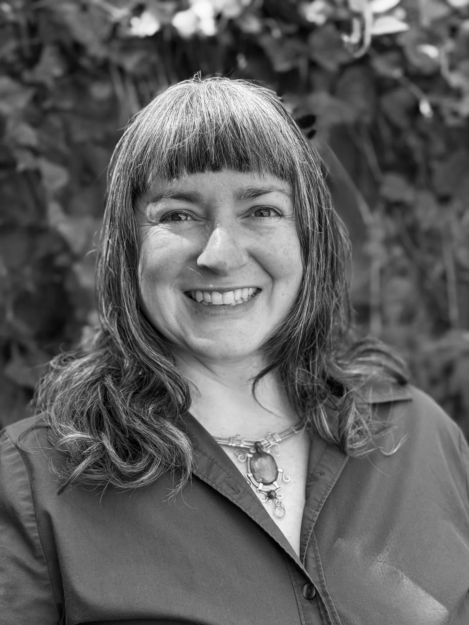 Black and white photo of Shannon Jontz, L.Ac, MTOM, wearing a crystal necklace and smiling warmly