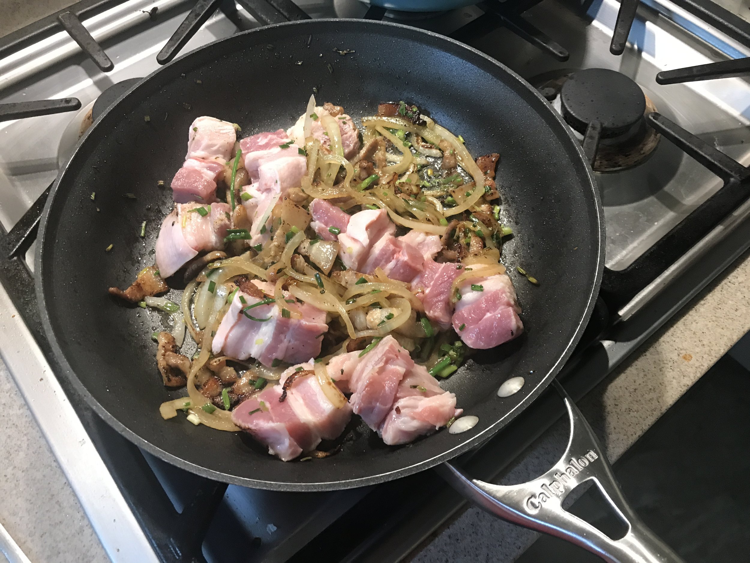  Add in chopped scallions, garlic, grated ginger and the larger pork belly pieces and brown them 