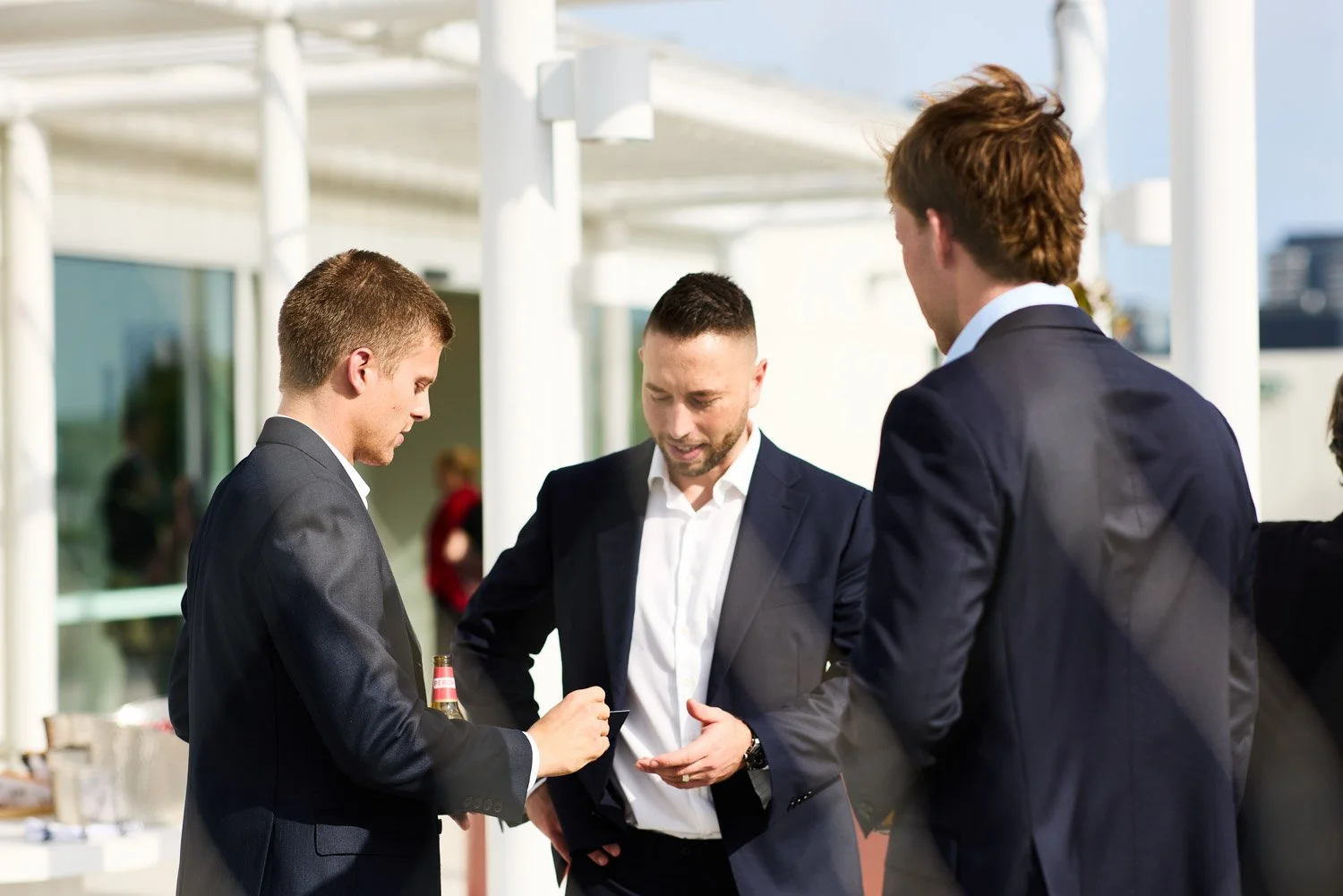 Three men in business suits having a conversation outdoors at a professional event.