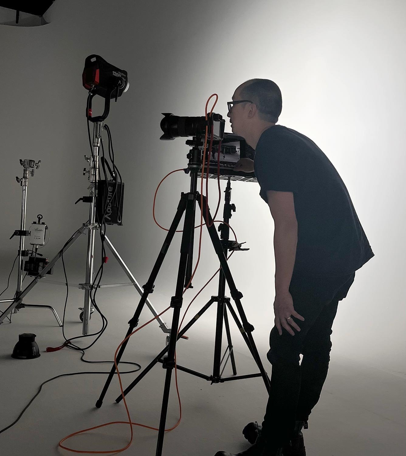 Ivan Lee the photographer  standing in front of camera equipment on a white studio backdrop photographing Caravans. Behind the scenes.