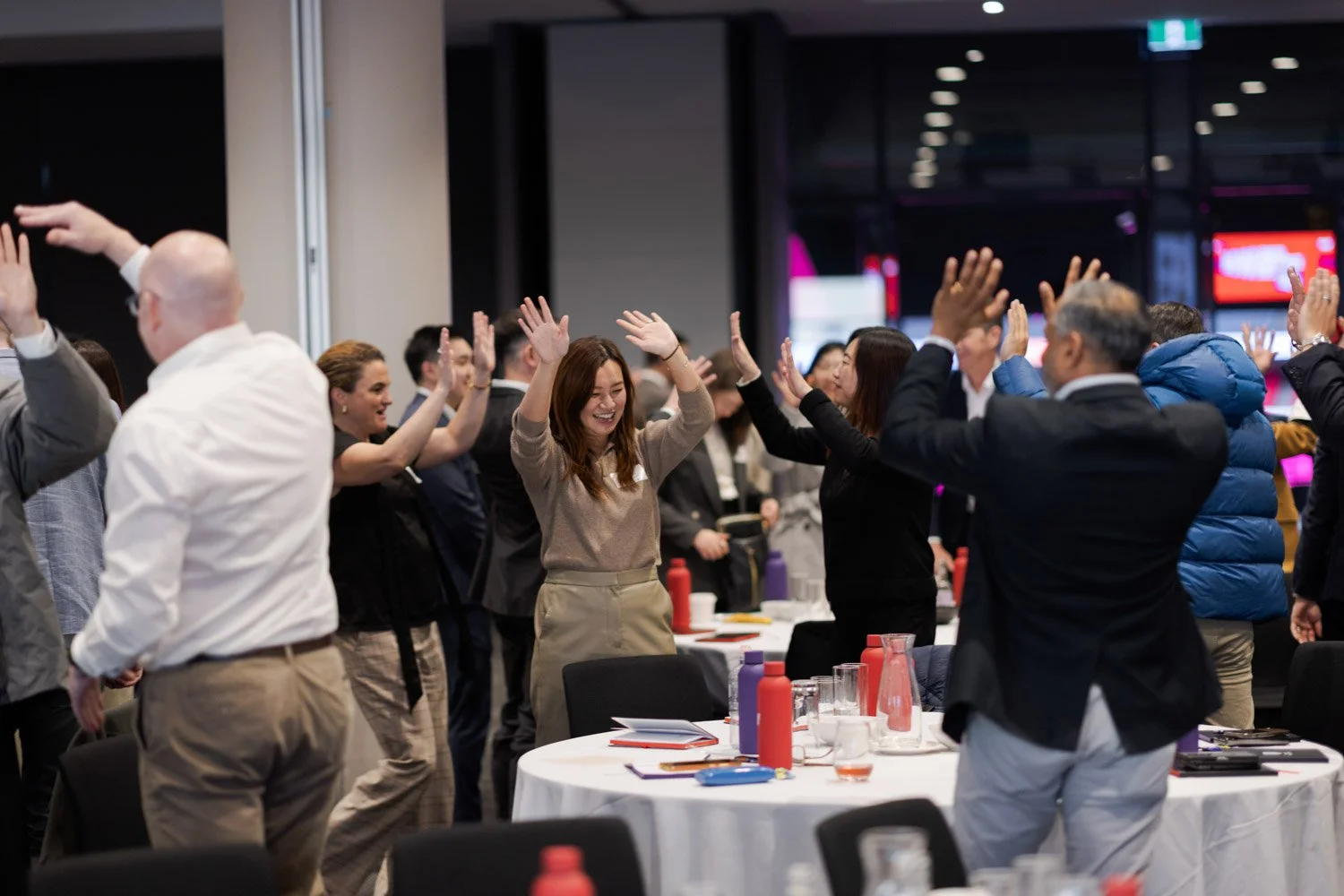 A group of business professionals in a conference room celebrating and high-fiving each other.