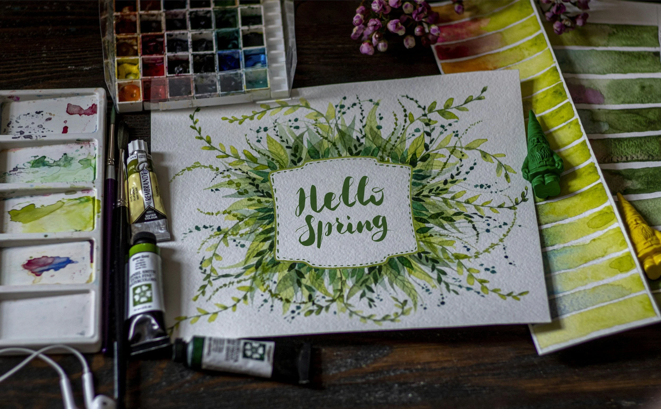 someone's water color workspace shows a handlettering of Hello Spring framed by a wild wreath of greenery in many shades of green