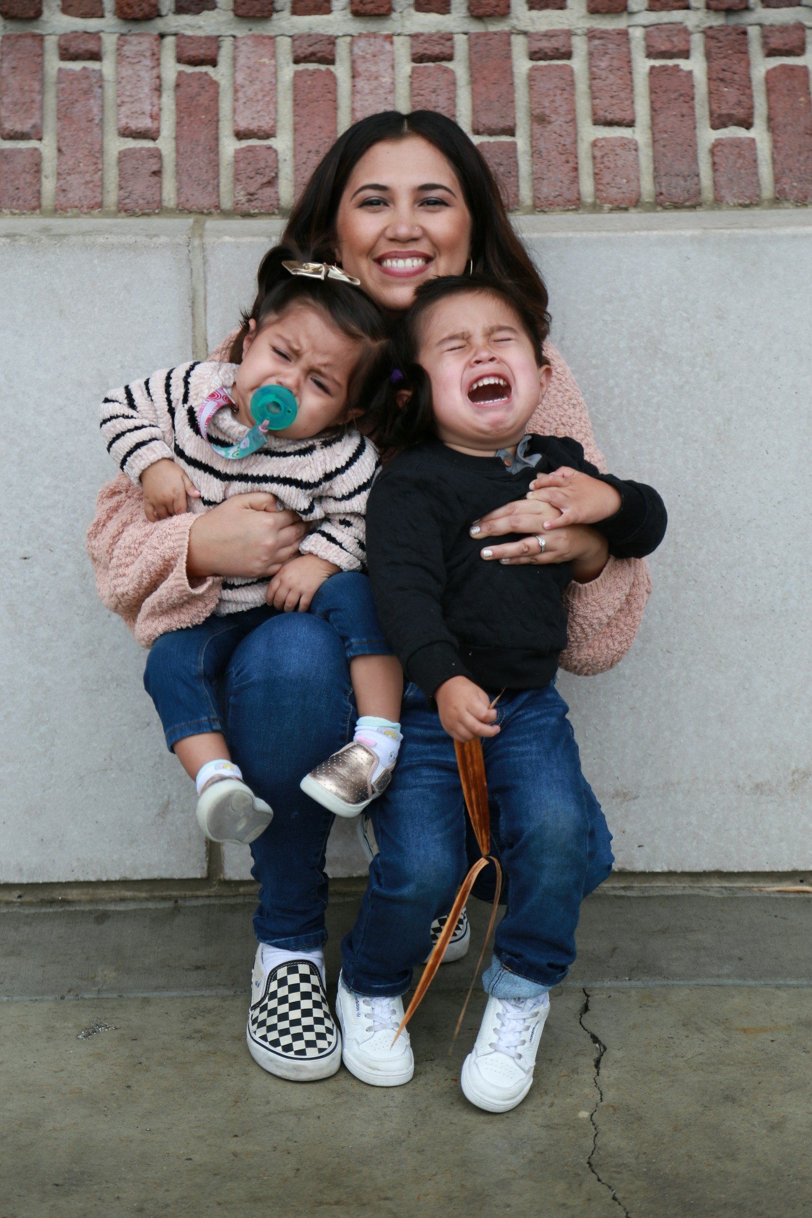 a mother with her two children smiles while they experience big emotions, a depiction of a woman holding their family unit together, carrying the mental load day after day , burnout support for moms is available in ferndale, MI