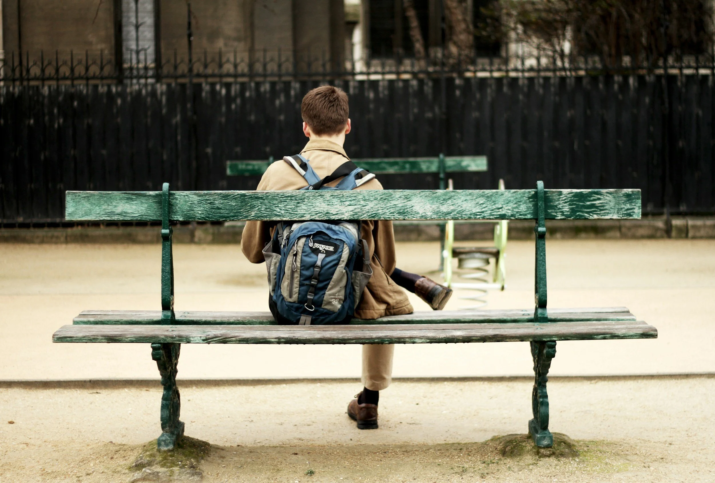 a teen sits alone on a school bench with his backpack. back to school nerves and anxiety can look similar