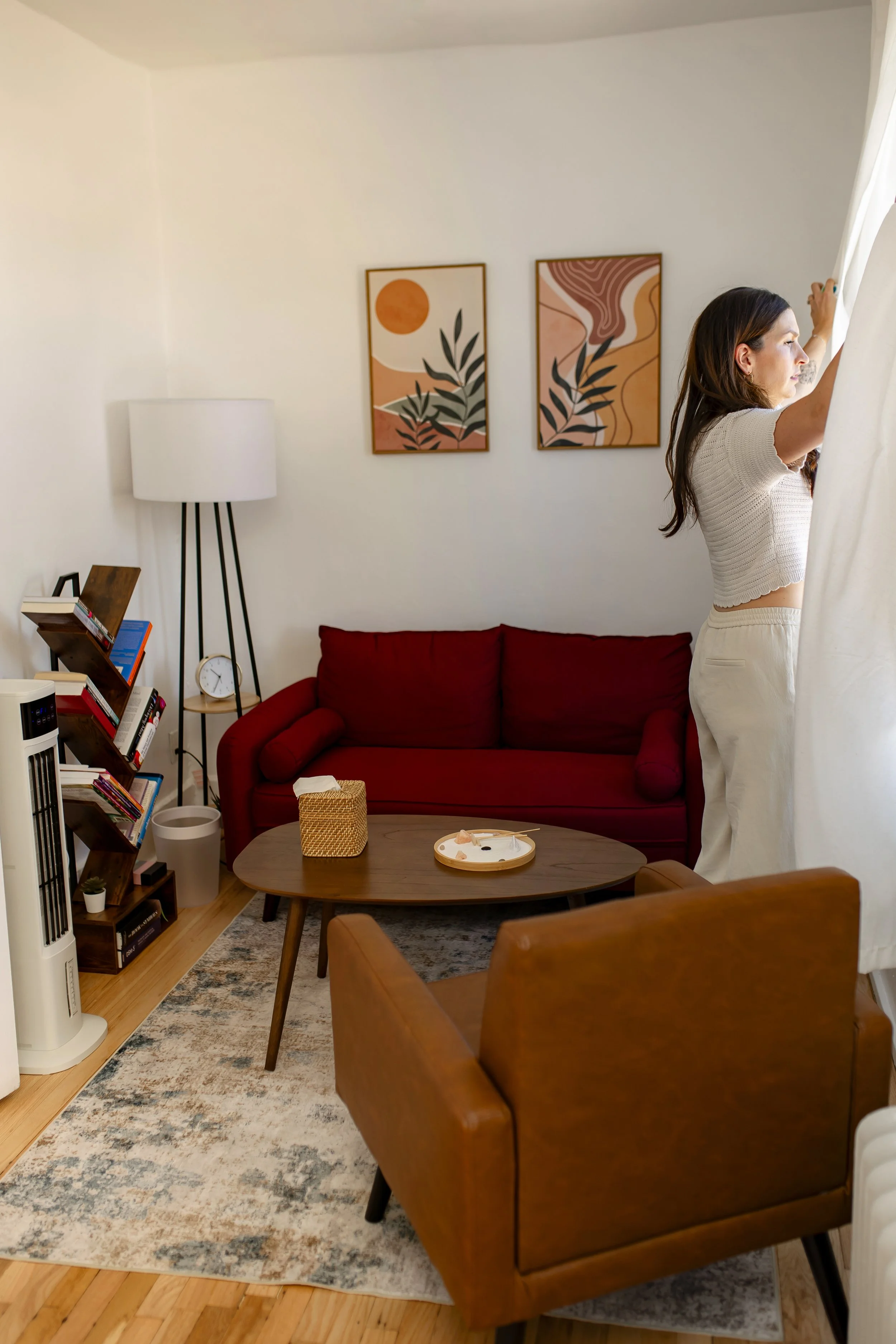 Kaity, CEO of Inspired Healing Therapy in Ferndale, Michigan, opens the curtains to let natural light into the new office space in Ferndale
