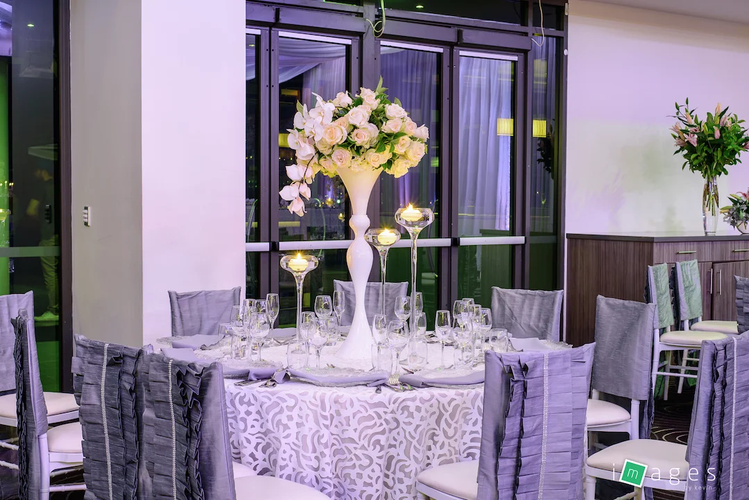 Waterview - Park Room - Guest table centrepiece consisting of white madonna vase with fresh florals and a set of 3 pavilion vases with floating candles, PB White Lori chair caps and Fiori tablecloths, clear glass charger plate with silver napkin.jpg
