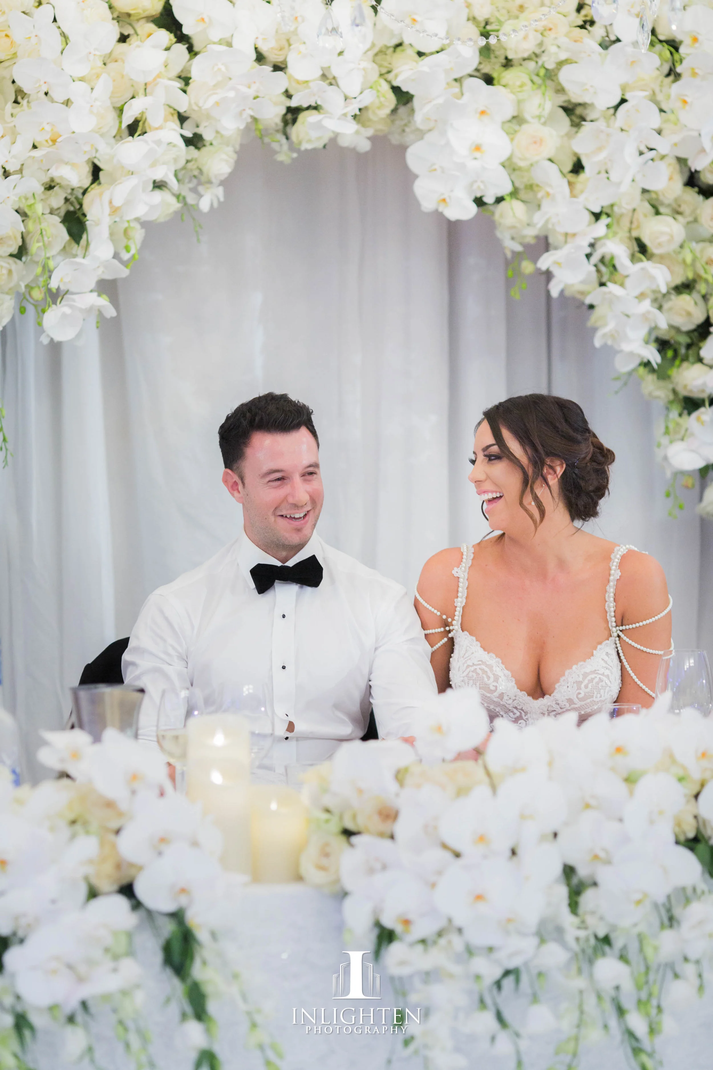 23 Kayla & Joe - Opera Point Marquee _Bridal table long_ low custom built frames_fresh flowers_LED pillar candles_white Windsor luxury linen.jpg