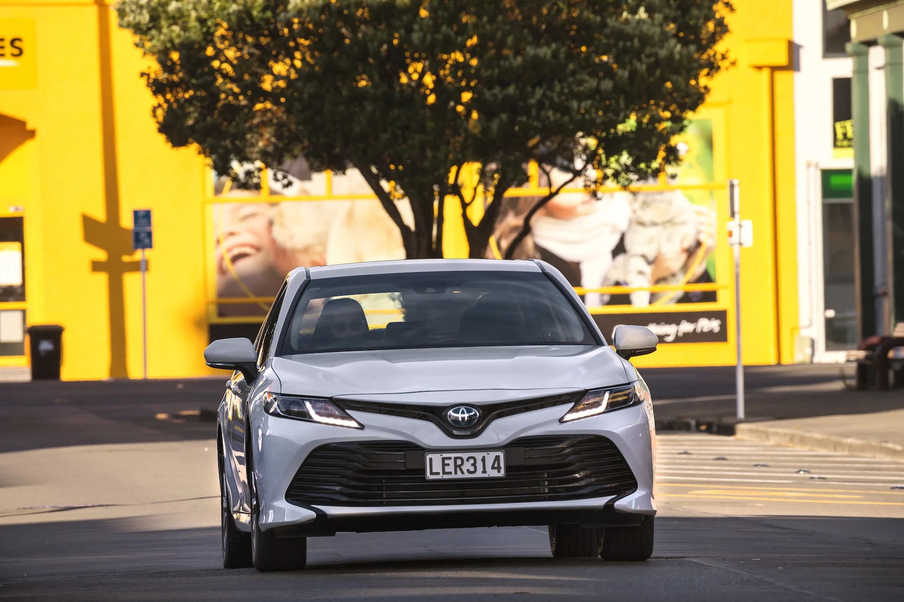 2018 Toyota Camry, GX hybrid, Glacier White, front shot.jpg