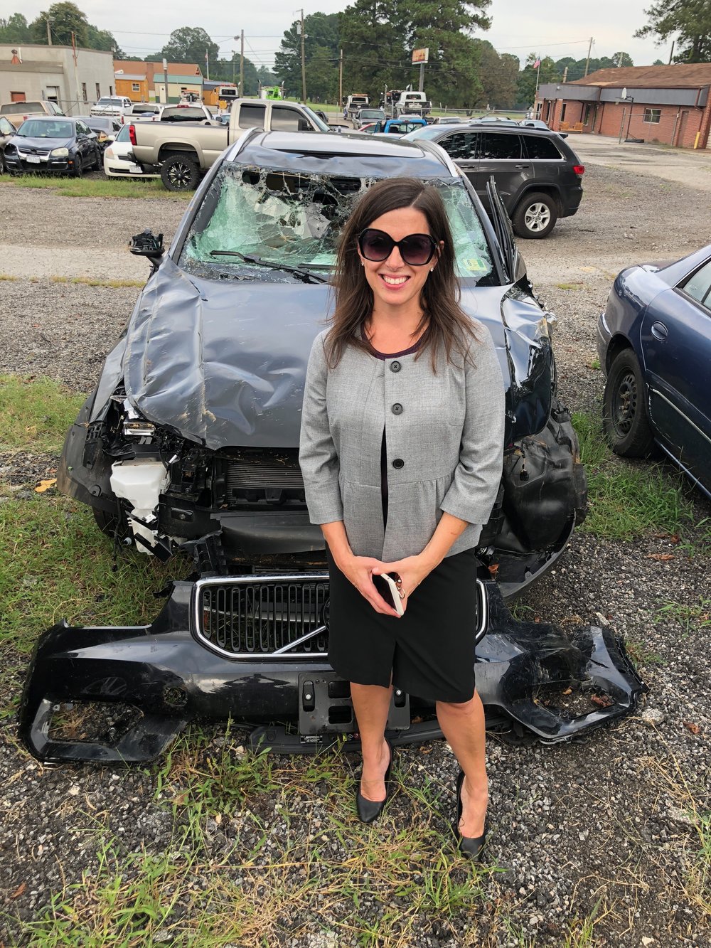  the badass survivor in front of the car that sacrificed itself to save her life 