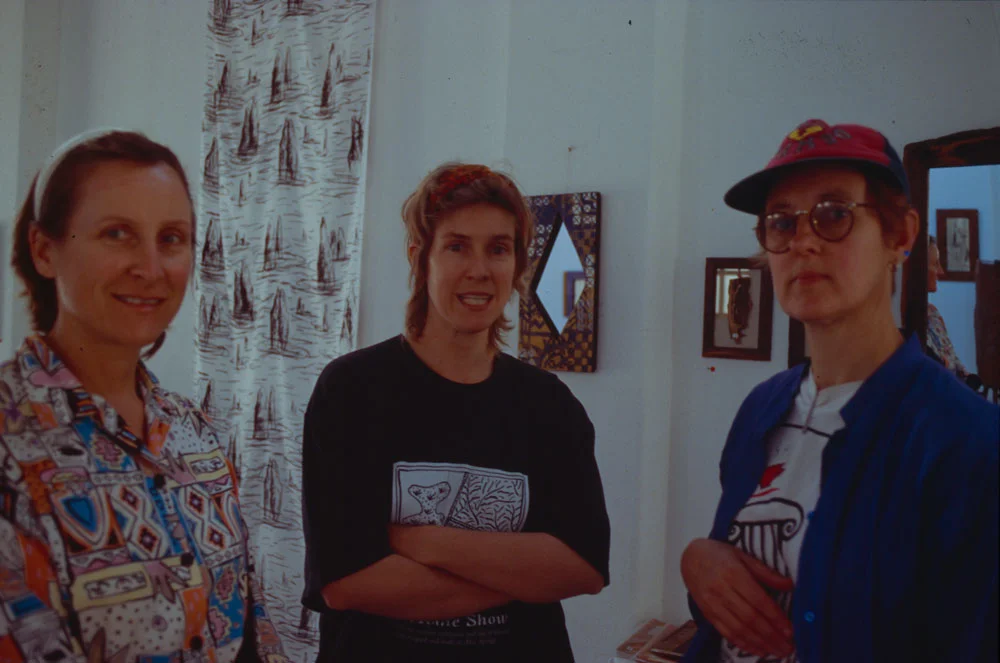 2/5 of the Founding Members: (L) Angela Gee & (R) Pip McManus, (M) Mary-Lou Nugent, with founding member Jan Mackay's hanging fabric artwork in the background. Circa 1995.