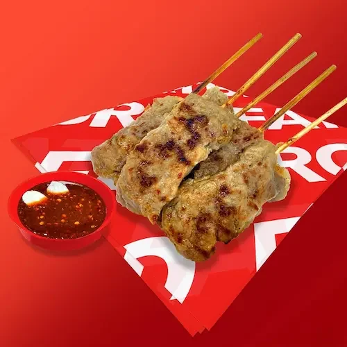 Four delicious grilled meat skewers from Fatbro served with a small bowl of sauce on red wrapping paper.