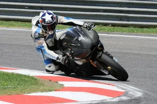 Motorcycle racer leaning into a turn on a racetrack, wearing a helmet and racing suit.