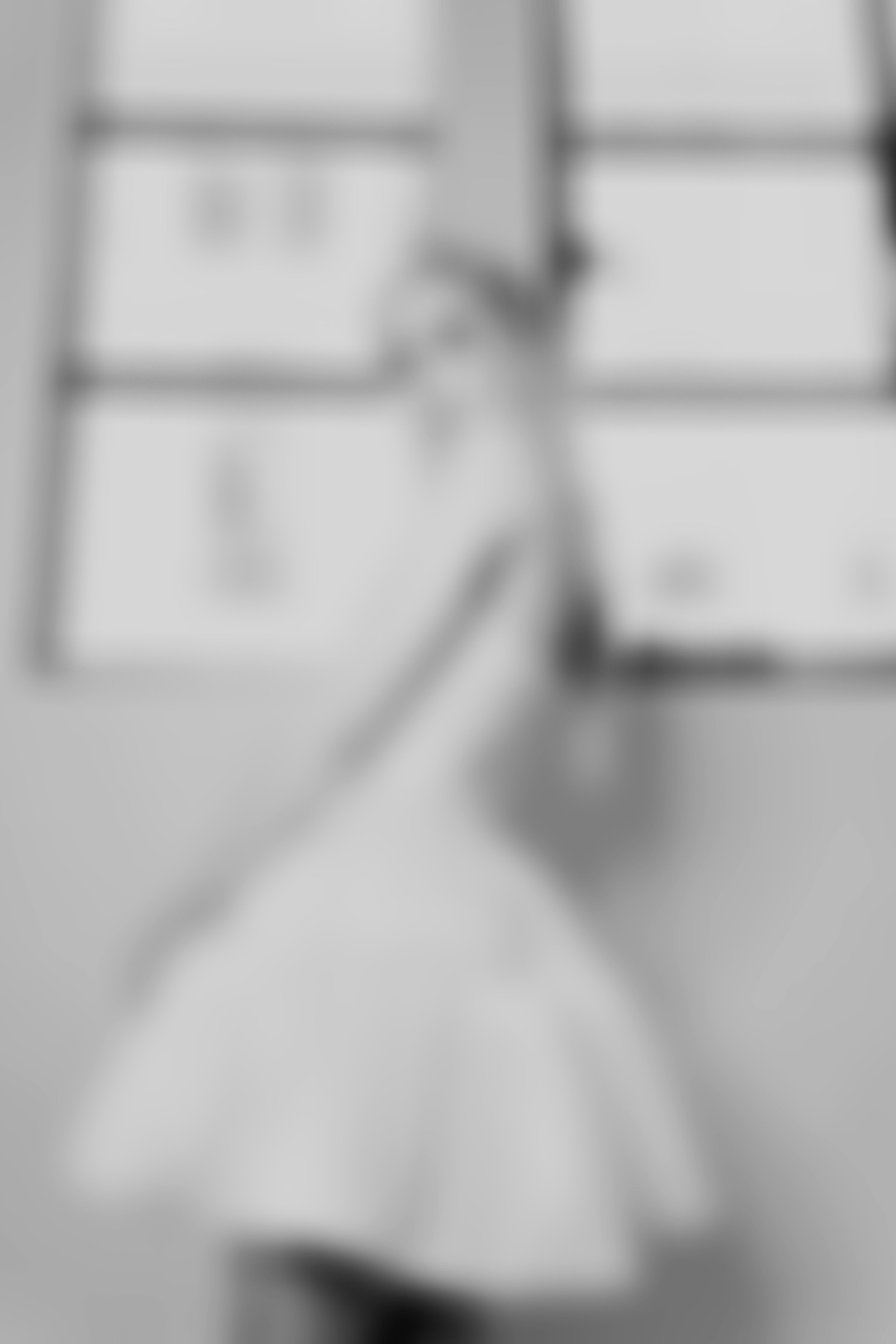 Blurred image of a person standing in a room with windows and a wall calendar.