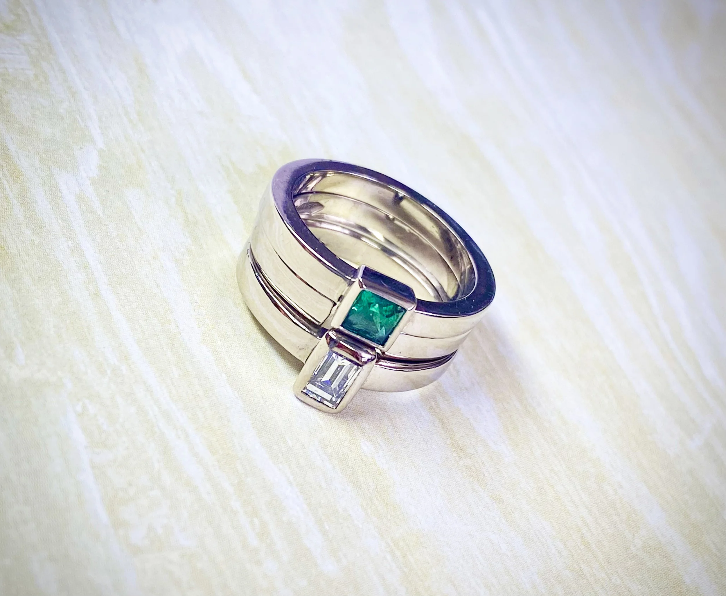 2 white gold rings set with a princess cut emerald and baguette diamond