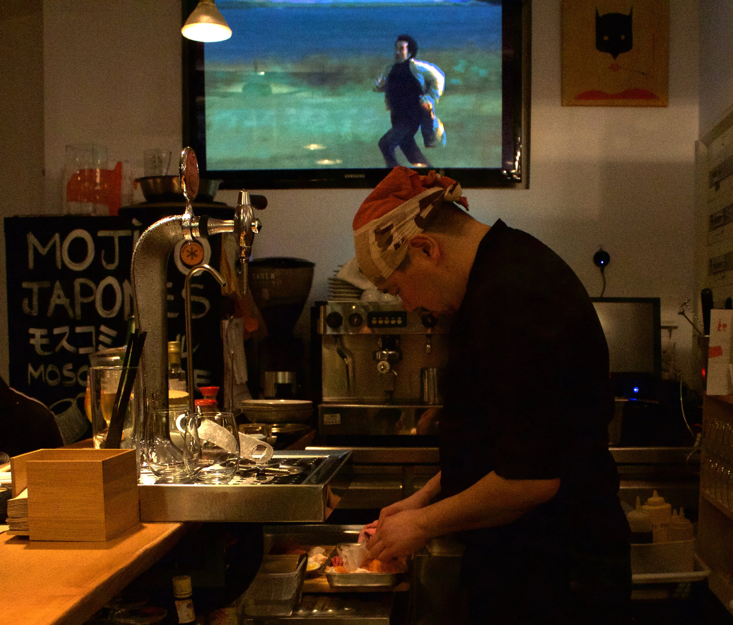Gohei Kishi hand preparing one of the 10 plates we enjoyed. Note the tense atmosphere in the movie playing above his head.
