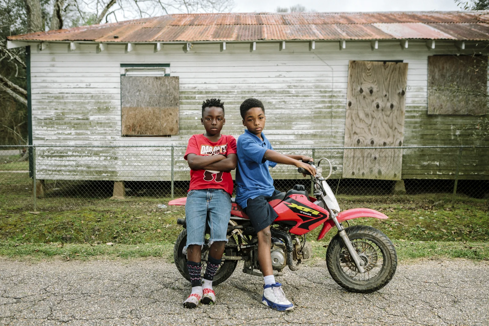 Reserve, LA - Feb 20, 2017 - Local residents Jaden James (9, L) and Lance Bovie (9) pause on Robinet Drive, less than a block from the fence line of the Dupont/Denka plant. Many of the homes in the area have been vacated as residents have either died or left town.
